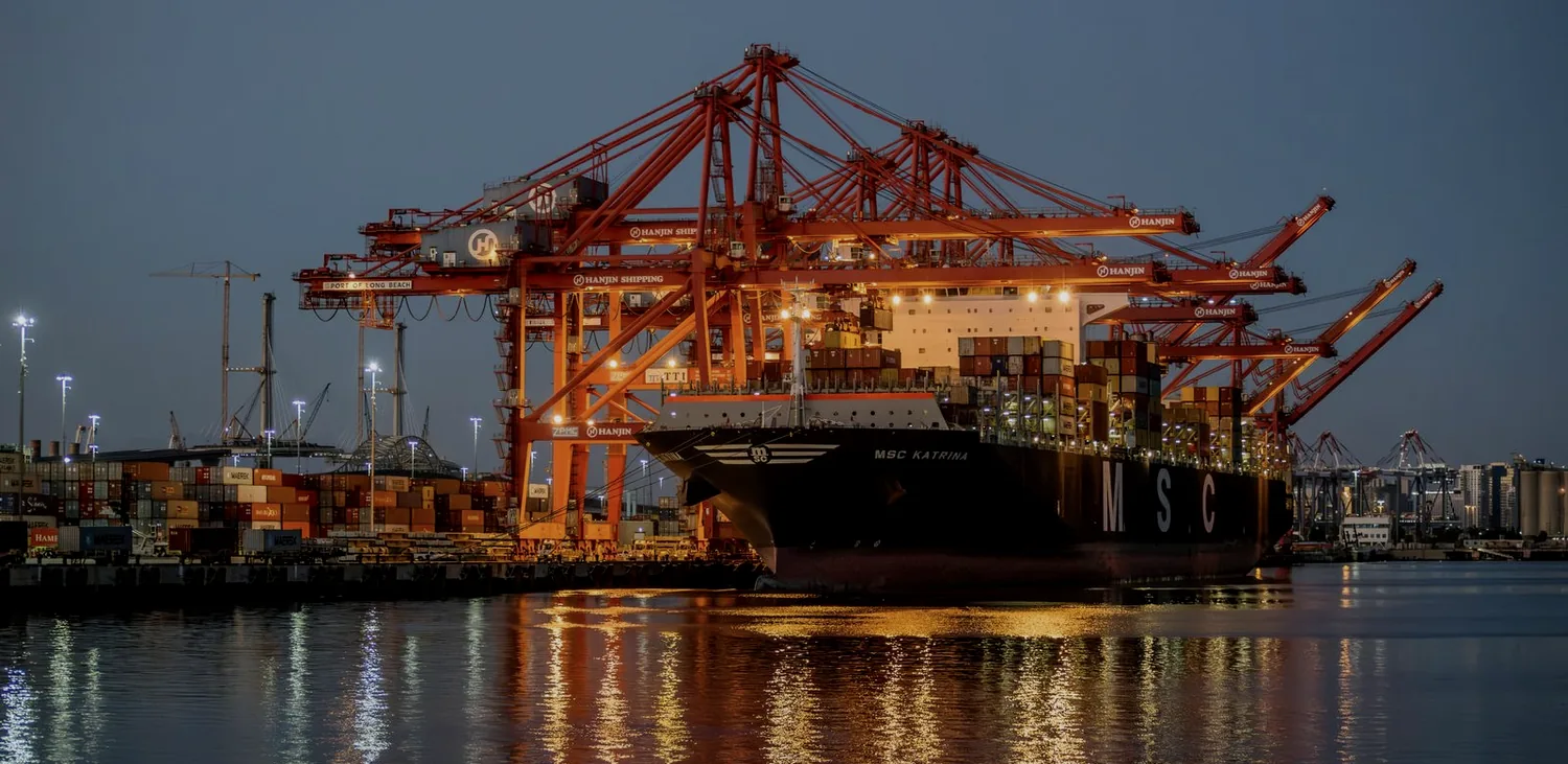 Terminal portuário à noite — guindastes sobre navio de contêineres